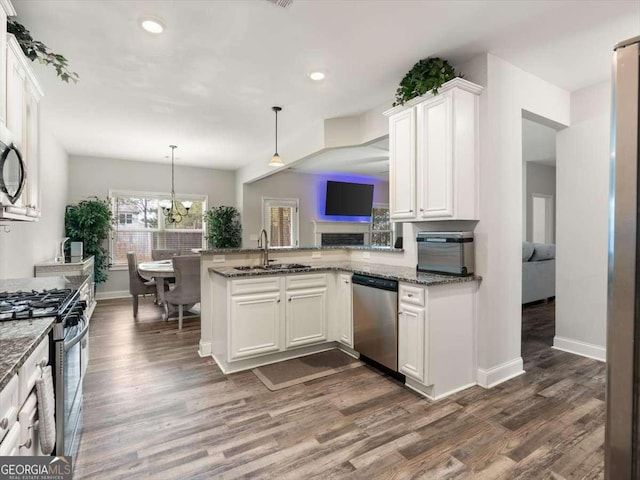 kitchen with appliances with stainless steel finishes, pendant lighting, white cabinetry, kitchen peninsula, and dark wood-type flooring