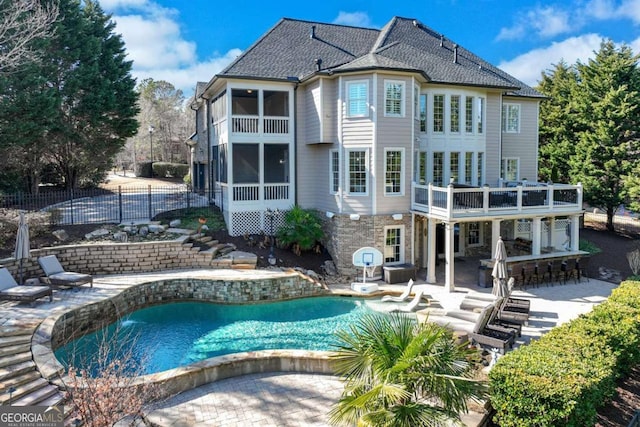 back of property featuring a balcony, a patio, a sunroom, and a bar