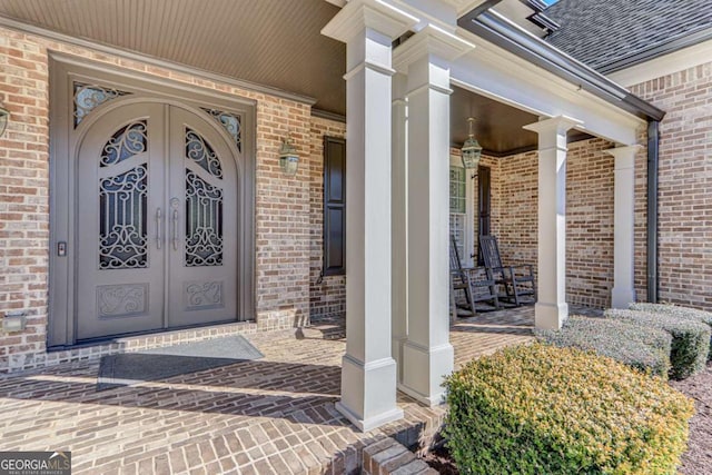 property entrance with covered porch and french doors