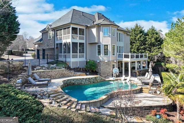 rear view of house featuring a patio, a sunroom, and a balcony