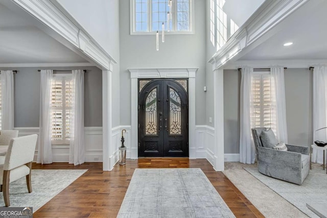 entrance foyer with dark hardwood / wood-style floors, ornamental molding, and french doors