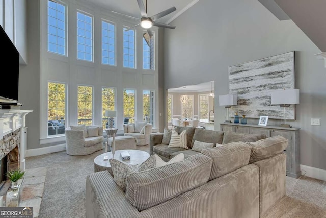 carpeted living room with ceiling fan, a fireplace, and a towering ceiling