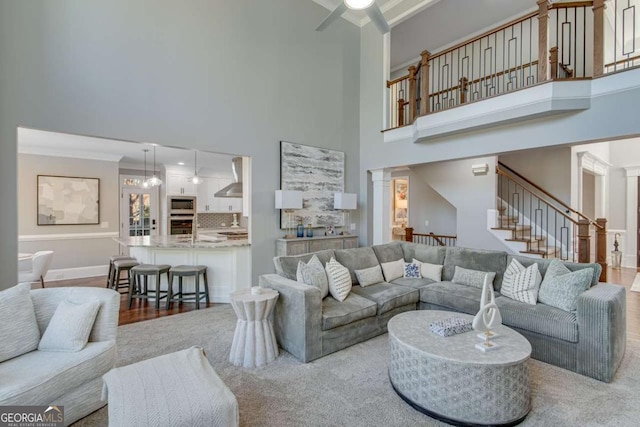 living room with a towering ceiling, ornamental molding, decorative columns, and hardwood / wood-style floors