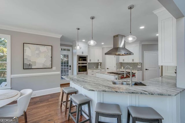 kitchen with white cabinetry, light stone counters, island range hood, and kitchen peninsula