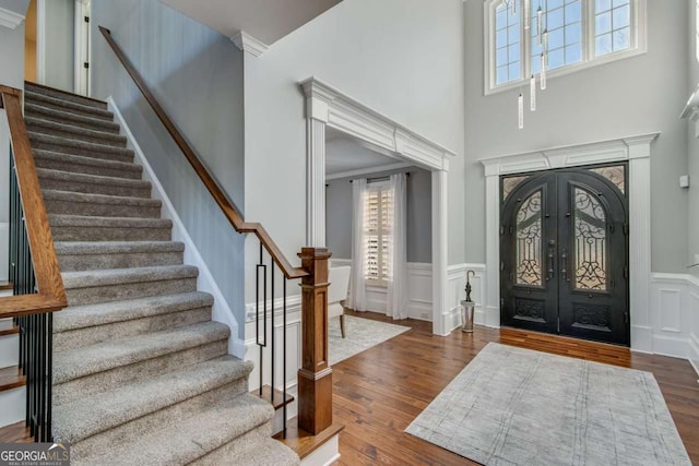 entryway with dark hardwood / wood-style floors, french doors, and a towering ceiling