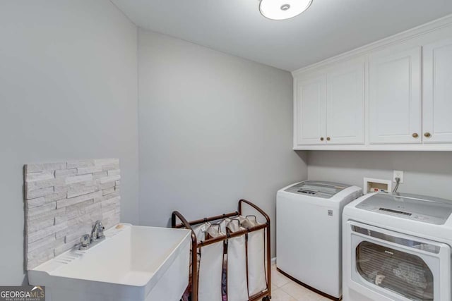 laundry area with washer and dryer, sink, light tile patterned floors, and cabinets