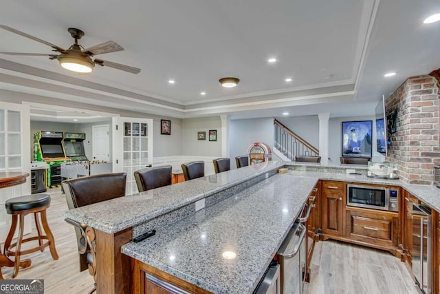 kitchen featuring wine cooler, a tray ceiling, a breakfast bar, and light stone countertops