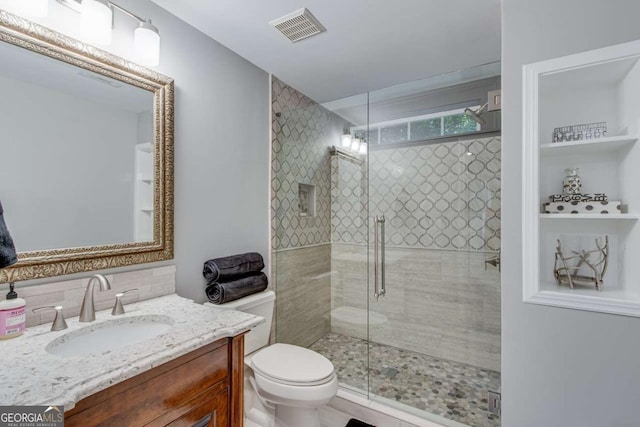 bathroom featuring decorative backsplash, vanity, an enclosed shower, and toilet