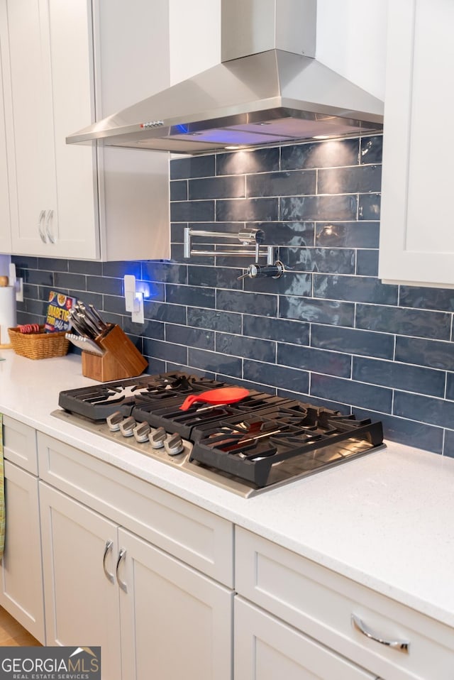 kitchen featuring island range hood, stainless steel gas stovetop, and white cabinets