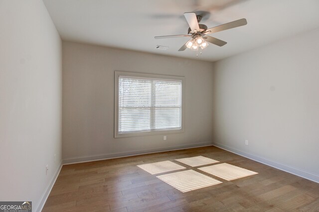 bedroom featuring ceiling fan, ensuite bathroom, a raised ceiling, and light carpet