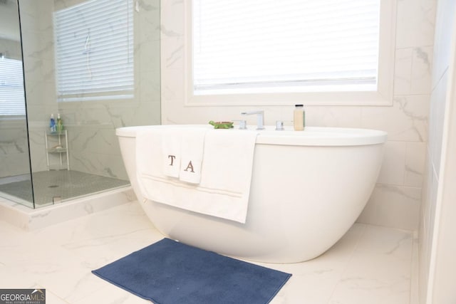 bathroom featuring plenty of natural light, tile walls, and a tile shower