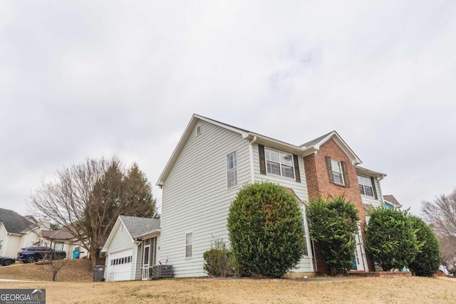 view of side of property featuring central AC, a garage, and a lawn