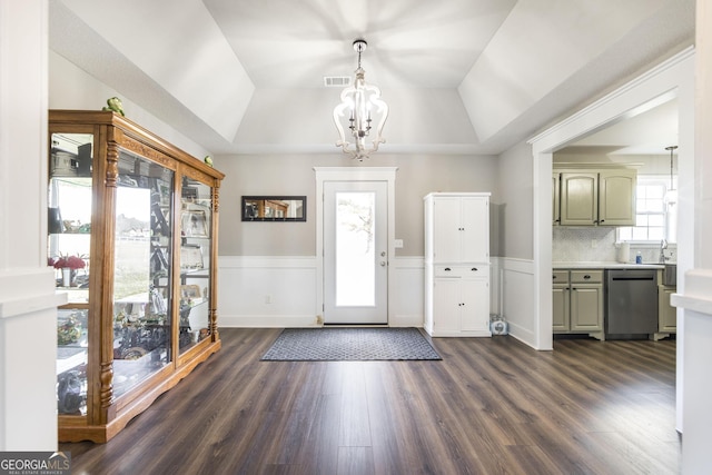 entrance foyer featuring a notable chandelier, dark wood-type flooring, and a raised ceiling