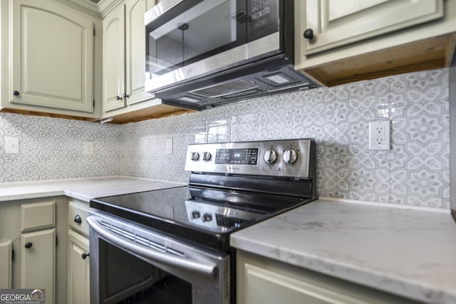 kitchen featuring cream cabinets, backsplash, and appliances with stainless steel finishes