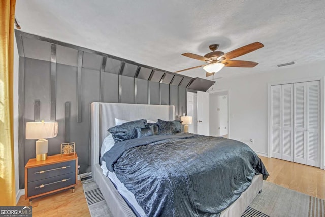 bedroom featuring ceiling fan, light hardwood / wood-style flooring, a closet, and a textured ceiling