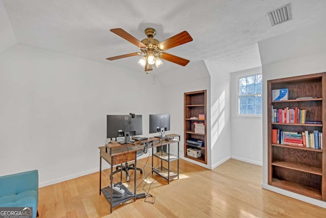 office area featuring built in shelves, ceiling fan, a textured ceiling, and light wood-type flooring