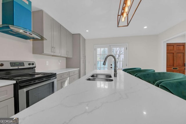 kitchen featuring stainless steel electric range oven, ventilation hood, sink, gray cabinetry, and light stone countertops