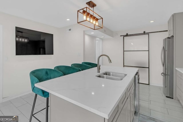 kitchen featuring sink, stainless steel appliances, a kitchen bar, decorative light fixtures, and a barn door