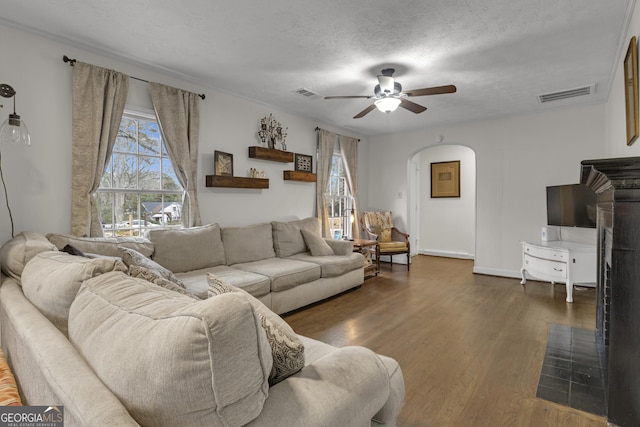 living room with dark wood-type flooring, ceiling fan, and a textured ceiling