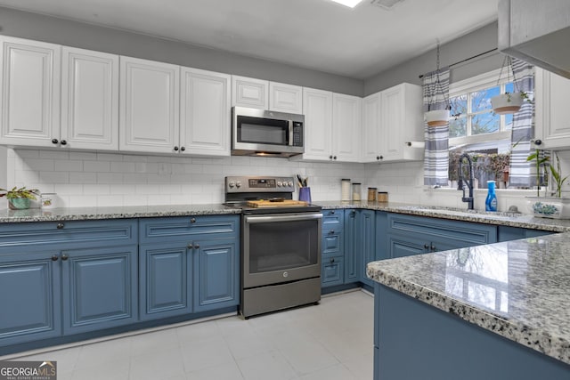 kitchen featuring white cabinetry, sink, decorative backsplash, stainless steel appliances, and blue cabinetry