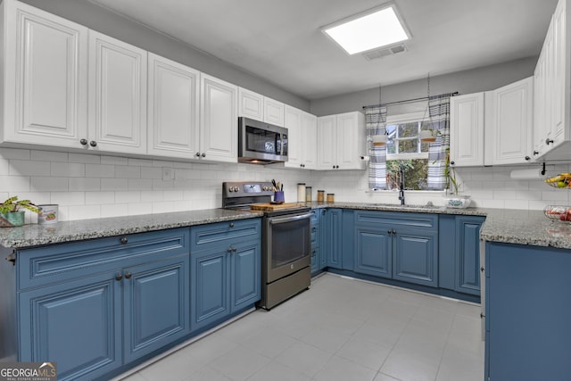 kitchen with white cabinetry, sink, blue cabinets, and appliances with stainless steel finishes