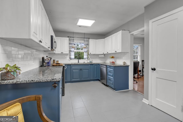 kitchen featuring stainless steel appliances, white cabinetry, blue cabinetry, and sink