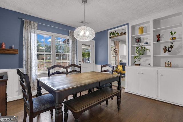 dining area featuring built in shelves, dark hardwood / wood-style floors, and a textured ceiling