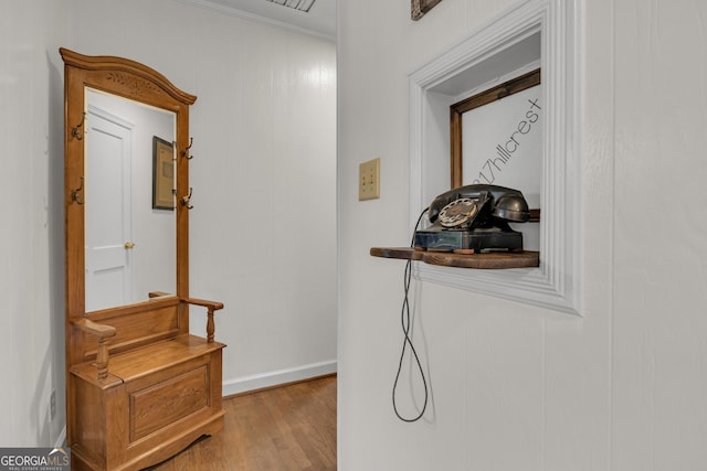 hallway with crown molding and light hardwood / wood-style flooring