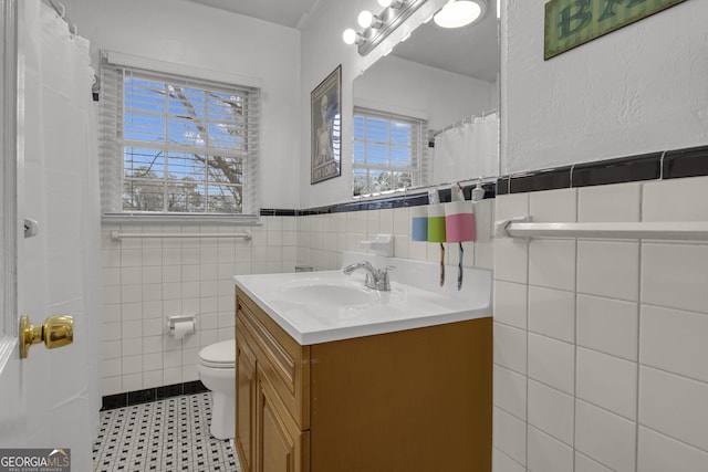 bathroom with vanity, tile walls, and toilet