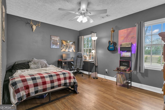 bedroom with ceiling fan, hardwood / wood-style floors, and a textured ceiling