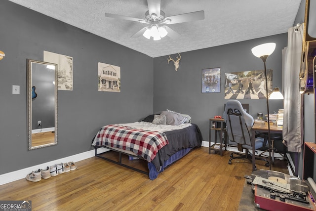 bedroom with ceiling fan, hardwood / wood-style floors, and a textured ceiling