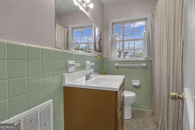 bathroom with vanity, a healthy amount of sunlight, tile walls, and toilet