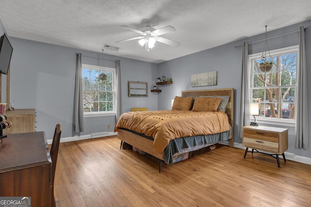 bedroom featuring ceiling fan, wood-type flooring, and a textured ceiling