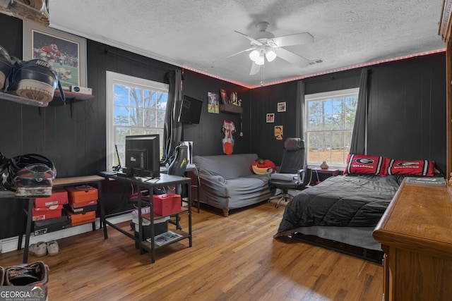 bedroom featuring ceiling fan, hardwood / wood-style floors, and a textured ceiling