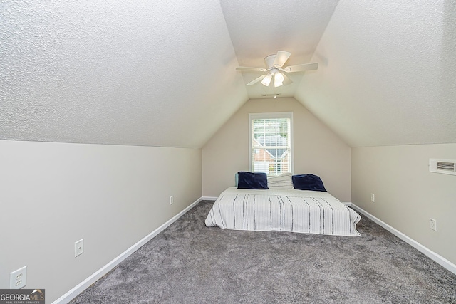 bedroom featuring vaulted ceiling, dark carpet, and a textured ceiling