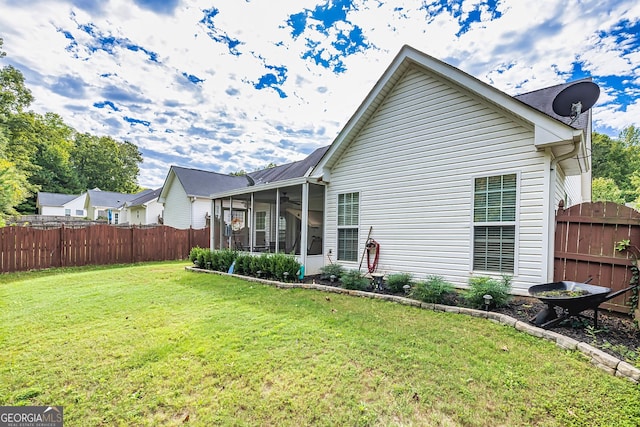 rear view of property featuring a yard, a sunroom, and ceiling fan