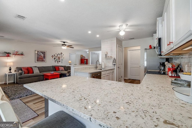 kitchen featuring sink, white cabinets, a kitchen breakfast bar, kitchen peninsula, and stainless steel appliances