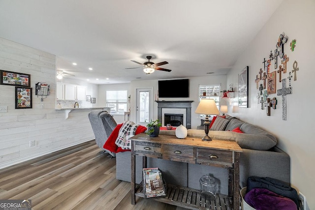 living room featuring hardwood / wood-style floors, ceiling fan, and wood walls