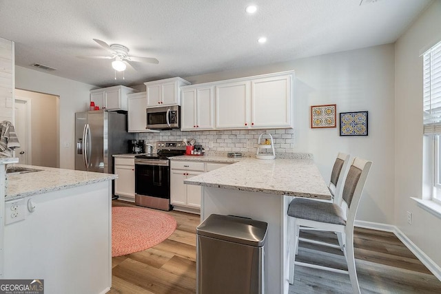 kitchen featuring stainless steel appliances, a kitchen breakfast bar, and white cabinets