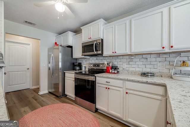 kitchen with light stone counters, white cabinetry, appliances with stainless steel finishes, and decorative backsplash