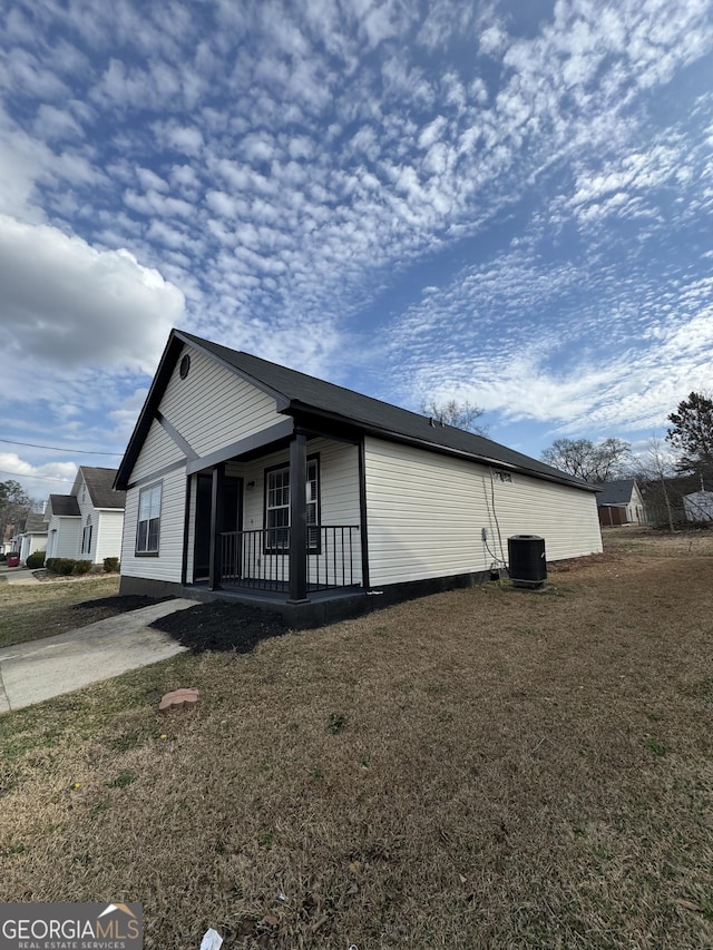 view of home's exterior with central AC unit, a lawn, and covered porch