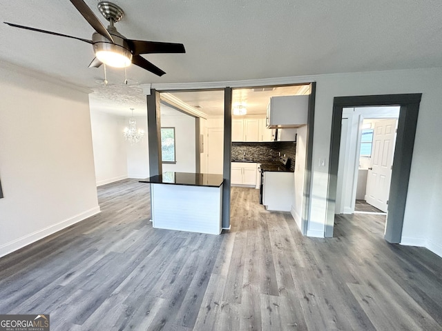 interior space featuring crown molding, wood-type flooring, ceiling fan with notable chandelier, and a textured ceiling