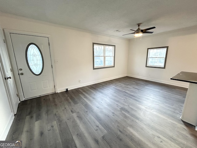 entrance foyer with dark hardwood / wood-style flooring, ceiling fan, ornamental molding, and a textured ceiling