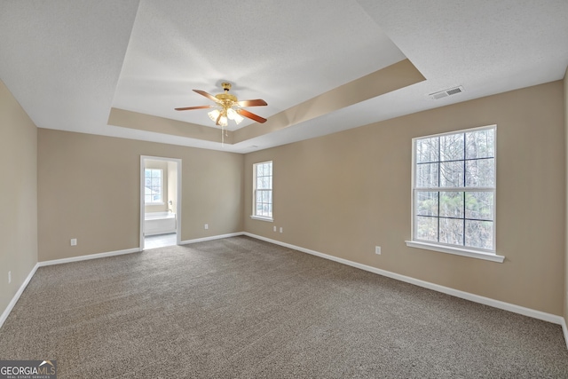 unfurnished room with ceiling fan, a tray ceiling, carpet, and a textured ceiling