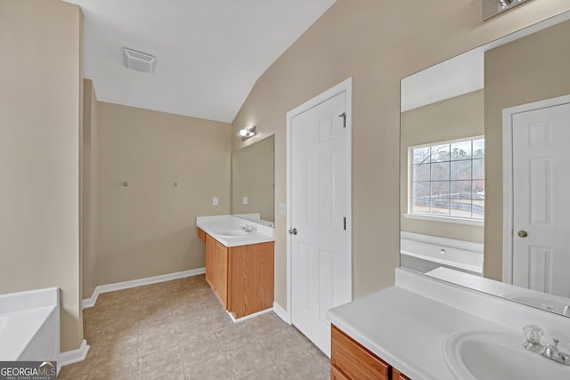 bathroom featuring a washtub, vanity, vaulted ceiling, and tile patterned floors