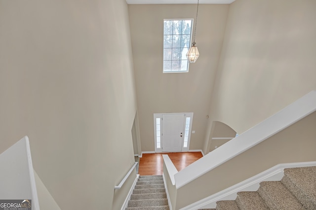 stairs with hardwood / wood-style floors and a high ceiling