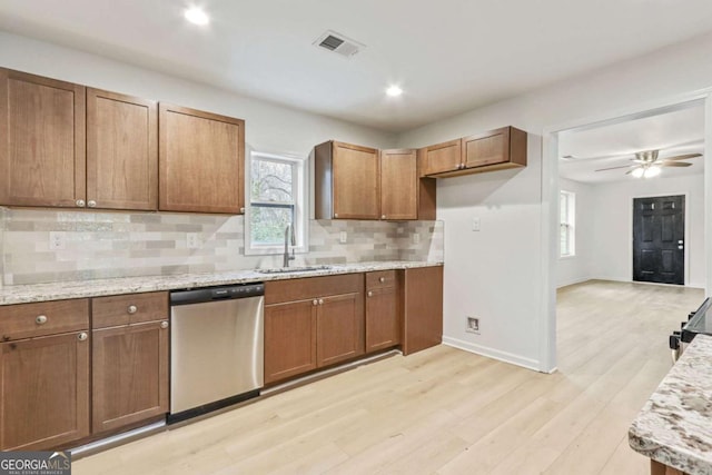 kitchen with sink, light hardwood / wood-style flooring, backsplash, stainless steel appliances, and light stone counters