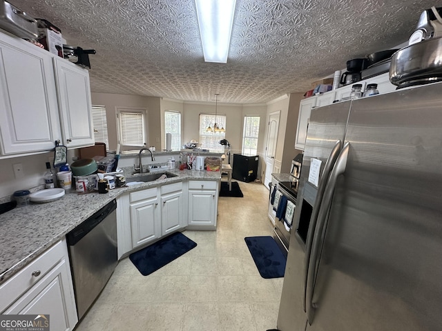 kitchen with sink, white cabinetry, light stone counters, decorative light fixtures, and appliances with stainless steel finishes