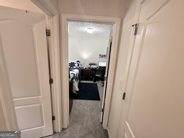 hall featuring light carpet and a textured ceiling