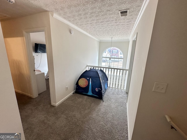 hall featuring dark colored carpet, ornamental molding, and a textured ceiling